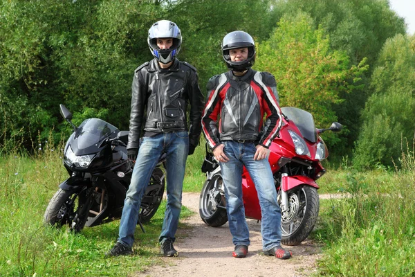 Two motorcyclists standing on country road near bikes — Stock Photo, Image