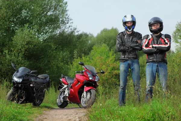 Due motociclisti in piedi sulla strada di campagna vicino alle biciclette — Foto Stock