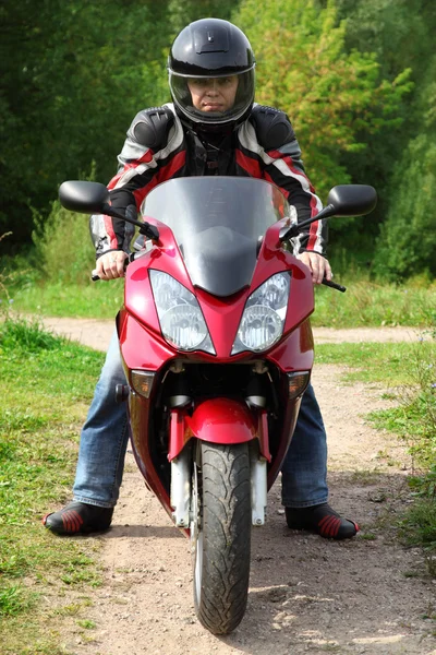 Мотоциклист стоит на проселочной дороге — стоковое фото