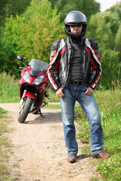Motorcyclist standing on country road near bike — Stock Photo, Image