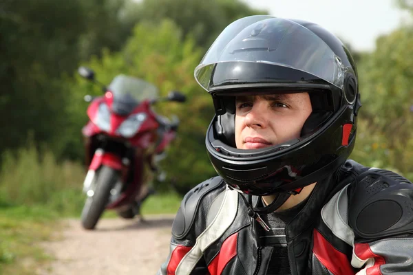 Motociclista e la sua moto su strada di campagna — Foto Stock