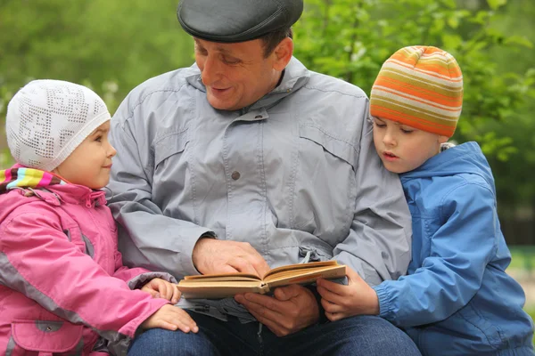 Grootvader leest boek voor jong geitje — Stockfoto