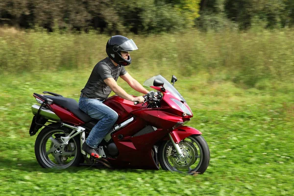 Motorradfahrer fährt auf Wiese — Stockfoto