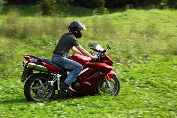 Motorradfahrer fährt auf Wiese — Stockfoto