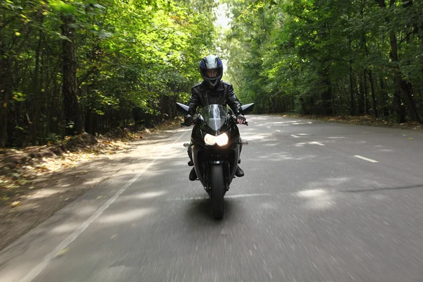Motocyklista jede na silnici, pohled zepředu — Stock fotografie