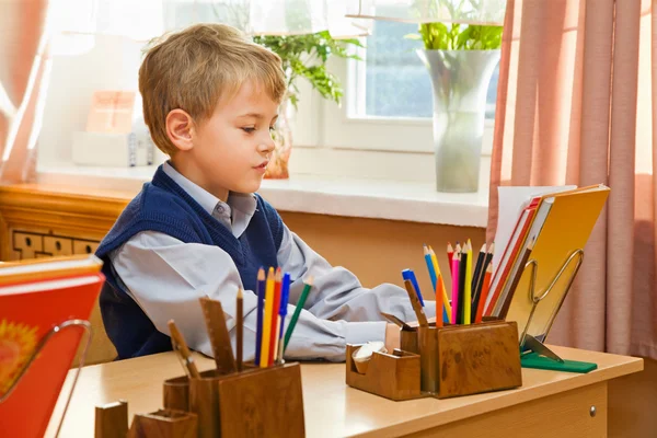 Молодой школьник сидит за школьным столом — стоковое фото