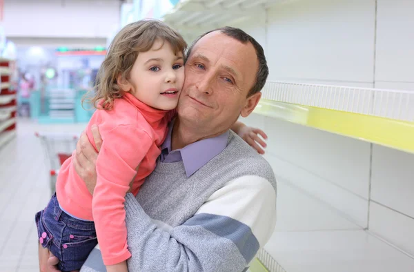 Anciano en estantes vacíos en la tienda con el niño en las manos —  Fotos de Stock
