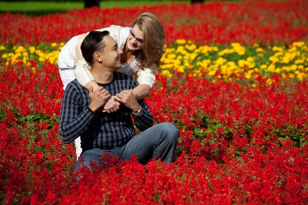 Homem e mulher de aparelho rindo nas flores — Fotografia de Stock