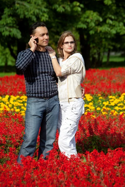 Young couple in flowering park — Stock Photo, Image