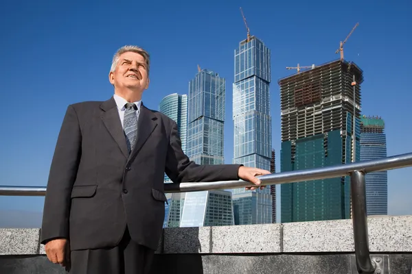 Mosolygó vezető férfi öltöny közelében felhőkarcoló építése — Stock Fotó