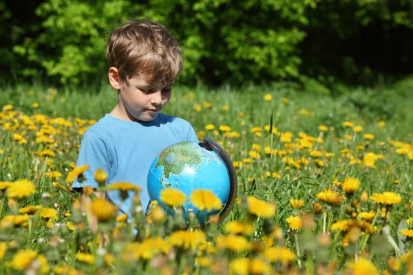 開花のタンポポの間で草原で地球を持つ少年 — ストック写真