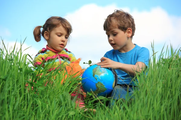 Girl and boy with globe on meadow — Stock Photo, Image