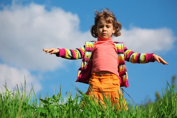 Маленькая девочка на траве против неба — стоковое фото