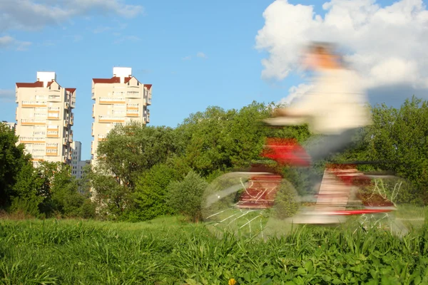 Велосипедист в движении размыть против деревьев и домов — стоковое фото