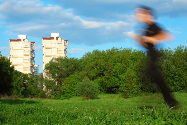 动感模糊男子在公园和两座建筑物中运行 — 图库照片