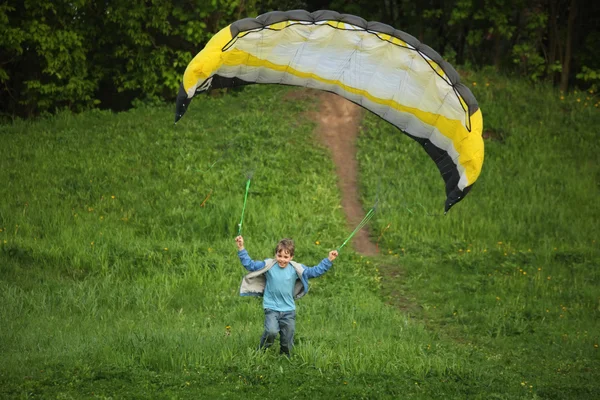 Pojken går från hill med fallskärm — Stockfoto