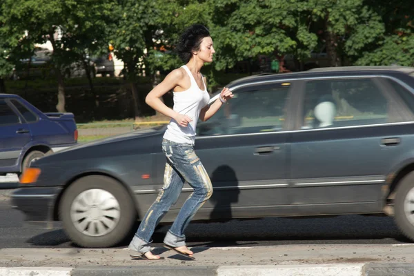 Девушка бегает по дороге среди автомобилей — стоковое фото