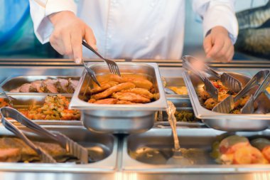 Hand of cook takes nippers fried meat in lunch counter at public clipart