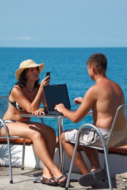 Family resting on sea with laptop clipart