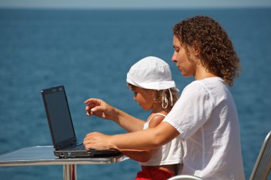 Family resting on sea with laptop clipart