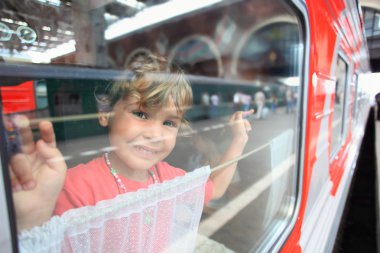 Smiling little girl look from train window clipart