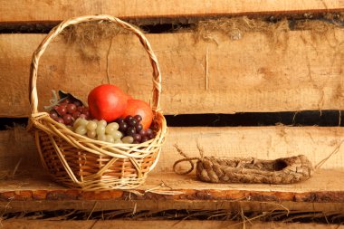Rural still life. Basket of grapes and apples, and bast shoes on clipart