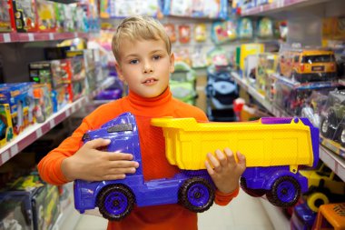 The boy in shop with toy truck in hands clipart