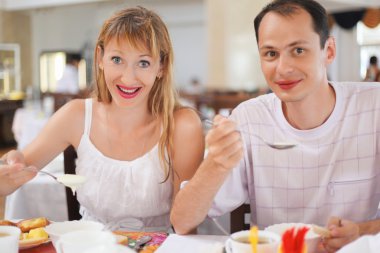 Married couple having breakfast at restaurant, eating cream whea clipart