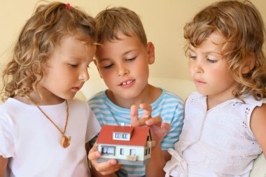 Children three together keeping in hands model of house in cosy clipart