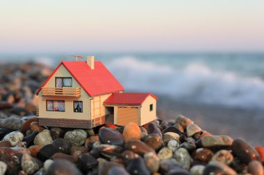 Model of house with garage on stony beach in evening clipart