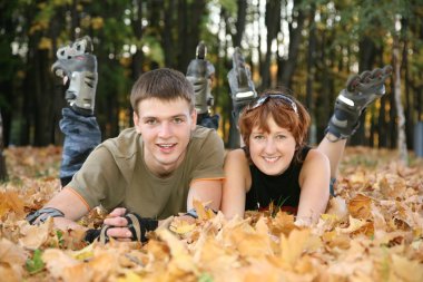 Young roller couple lies in park clipart