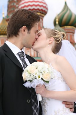 Bride and fiance are kissed against the background of temple Vasiliya Bless clipart