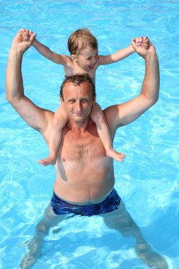 Grandfather in pool holds granddaughter on shoulders clipart