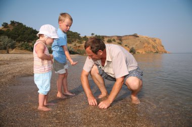 Grandfather with grandsons on beach clipart