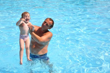 Grandfather standing in pool holds granddaughter clipart