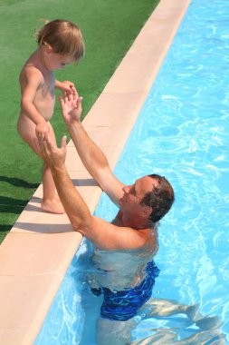 Girl stand on the edge of pool near of grandfather clipart