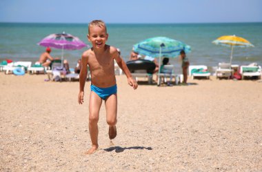 The boy runs on a beach. clipart