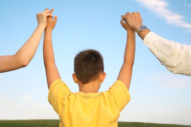 Child, who holds for the hands of parents against the background of the sky clipart