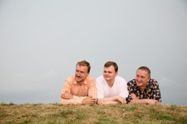 Three men, laying on the grass clipart