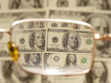 Dollars by the closeup through the eyeglasses clipart