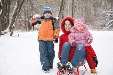 Mother with children in park at winter clipart