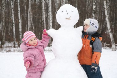 Boy and girl make snowman clipart