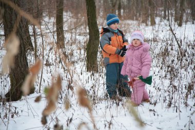 Brother with sister in forest in winter clipart