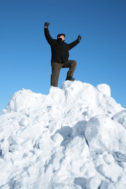 Elderly man on top of snow hill with hand up