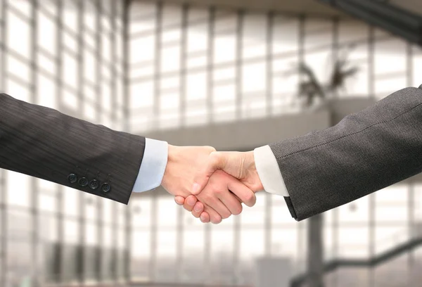 Shaking hands with wrists in hall of business center — Stock Photo, Image