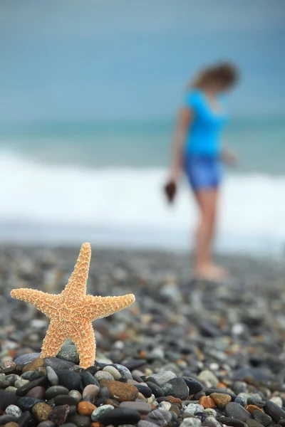 Starfish and young girl on stone seacoast — Stock Photo, Image