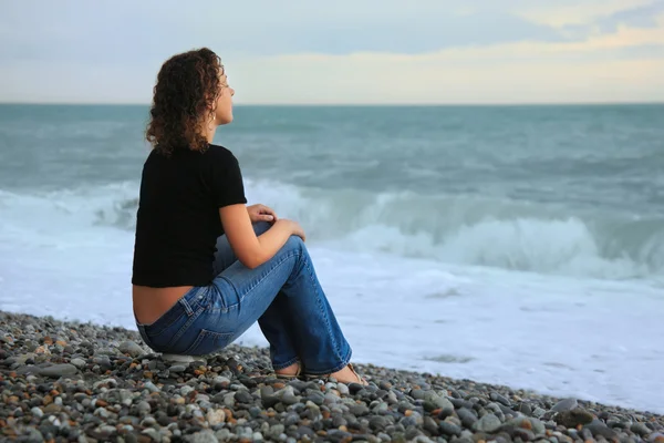 Schöne Frau am steinernen Meeresufer, auf dem Rücken sitzend — Stockfoto