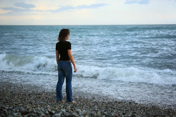Schöne Frau am steinernen Meeresufer, zurückstehend — Stockfoto