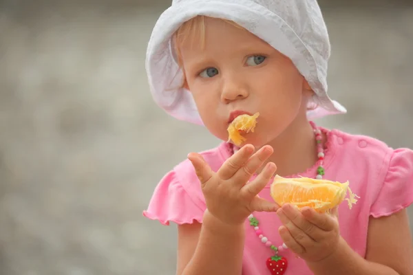 Liten flicka äter apelsin — Stockfoto