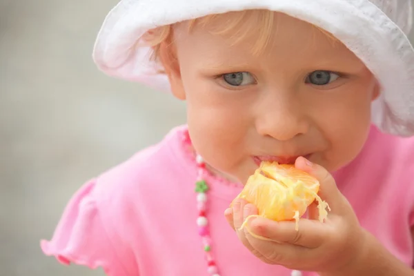 Liten flicka äter apelsin — Stockfoto